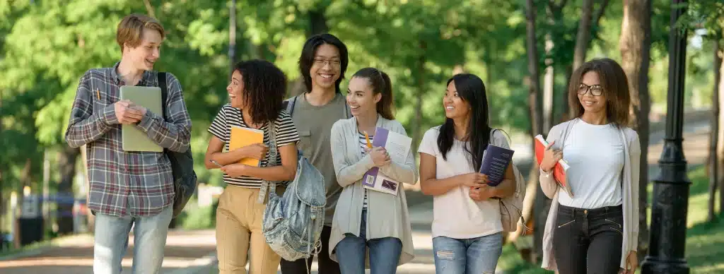 Groupe d'étudiants souriants marchant ensemble en plein air.