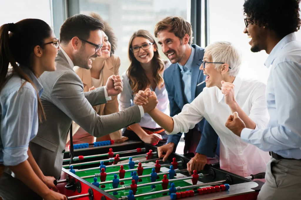 Groupe d'amis jouant au baby-foot avec enthousiasme.