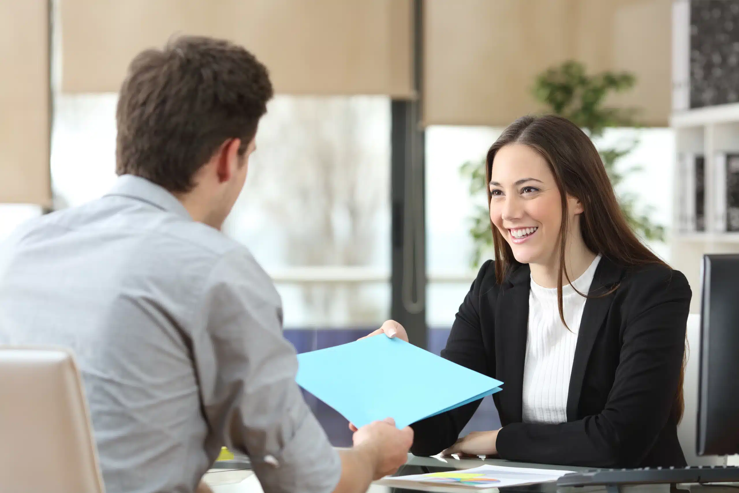 Femme souriante remet un document à un homme.