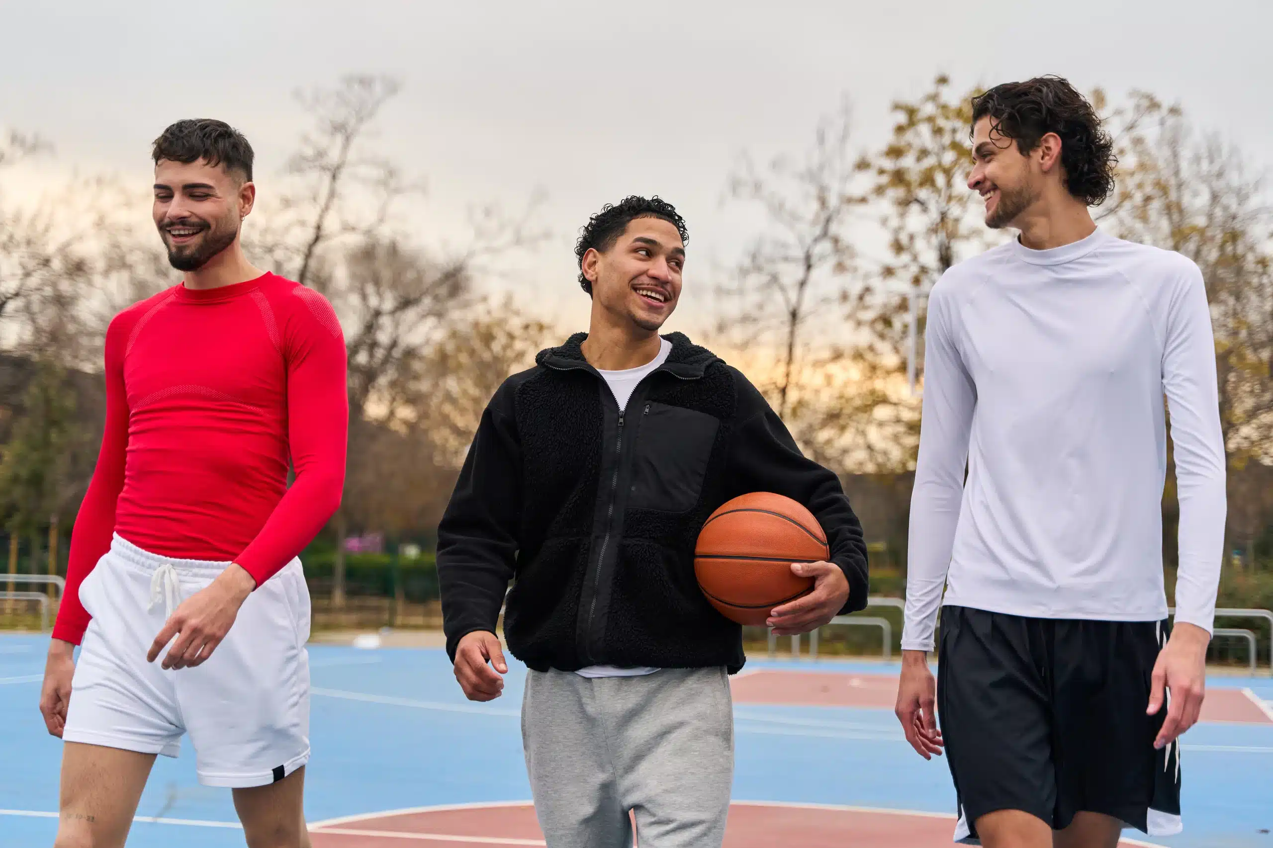 Trois amis marchant sur un terrain de basketball.