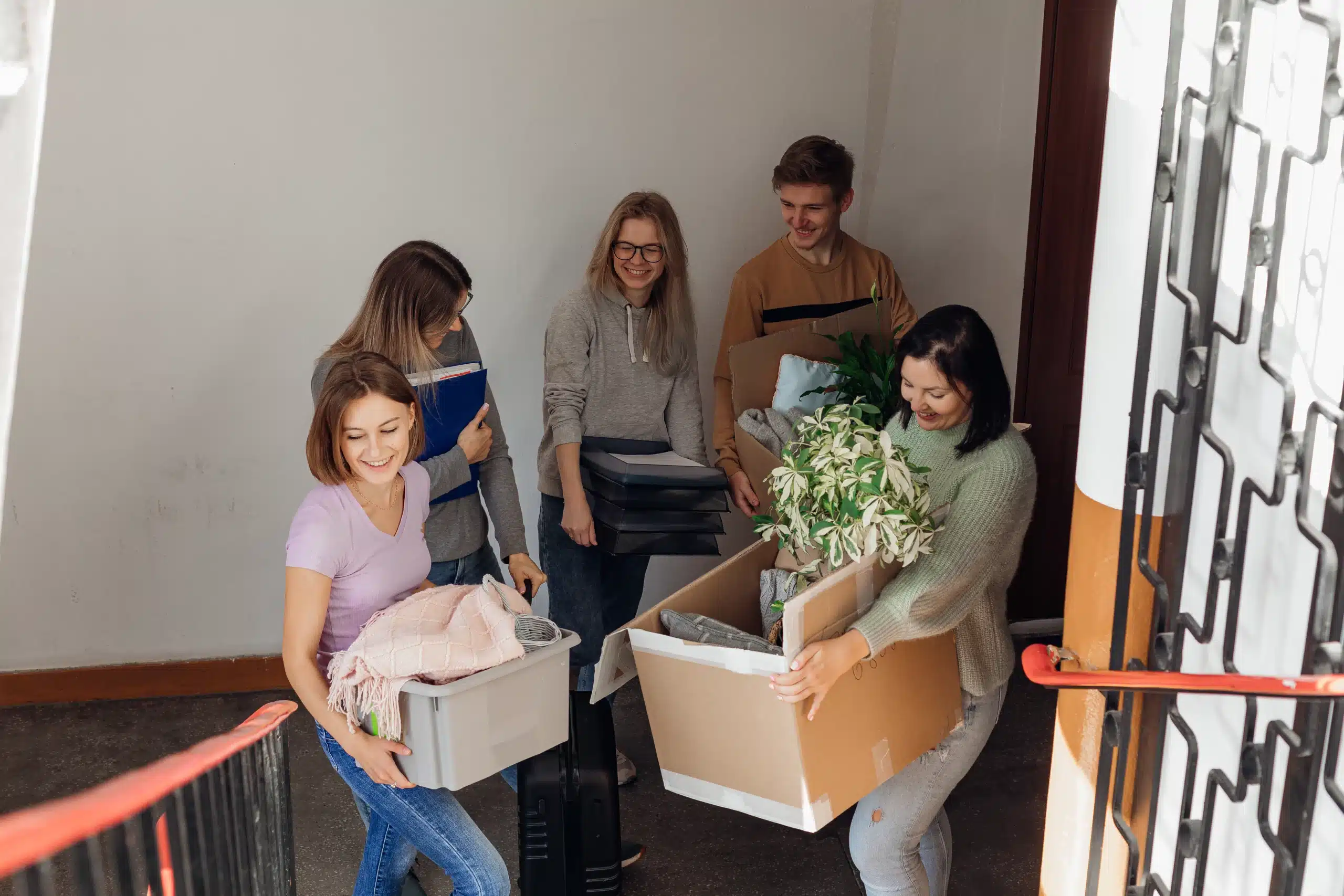 Groupe d'amis portant des cartons dans les escaliers.