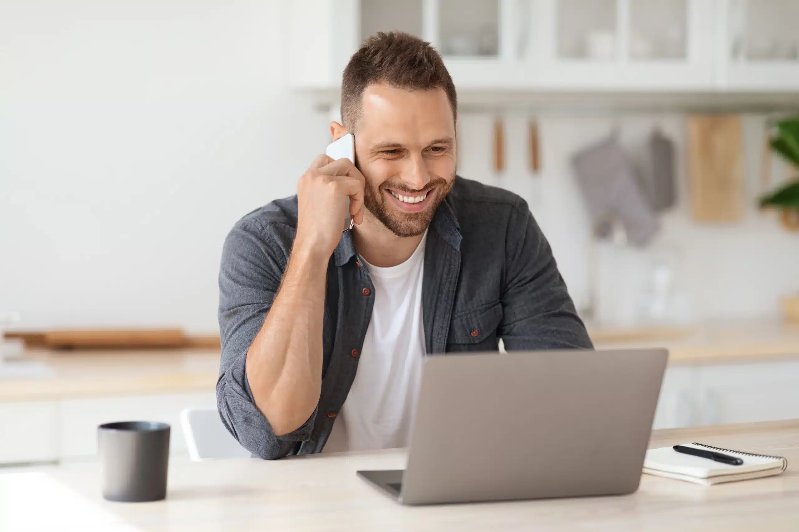 Homme souriant au téléphone devant un ordinateur