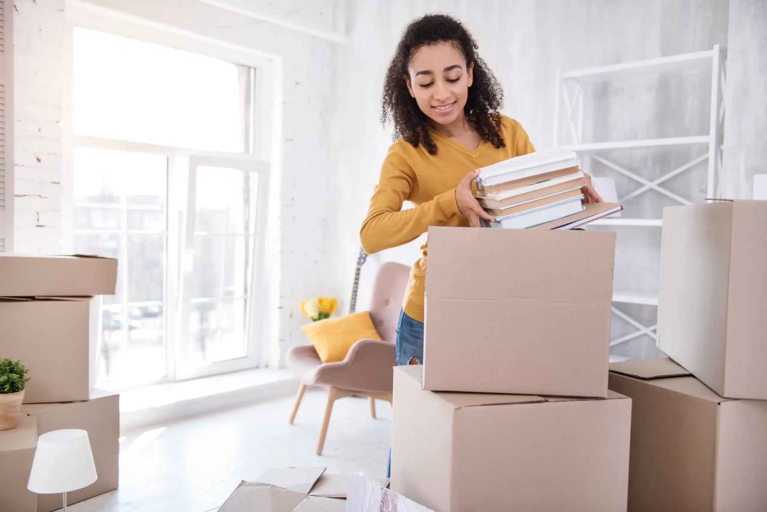 Femme déballant des livres dans un nouvel espace.